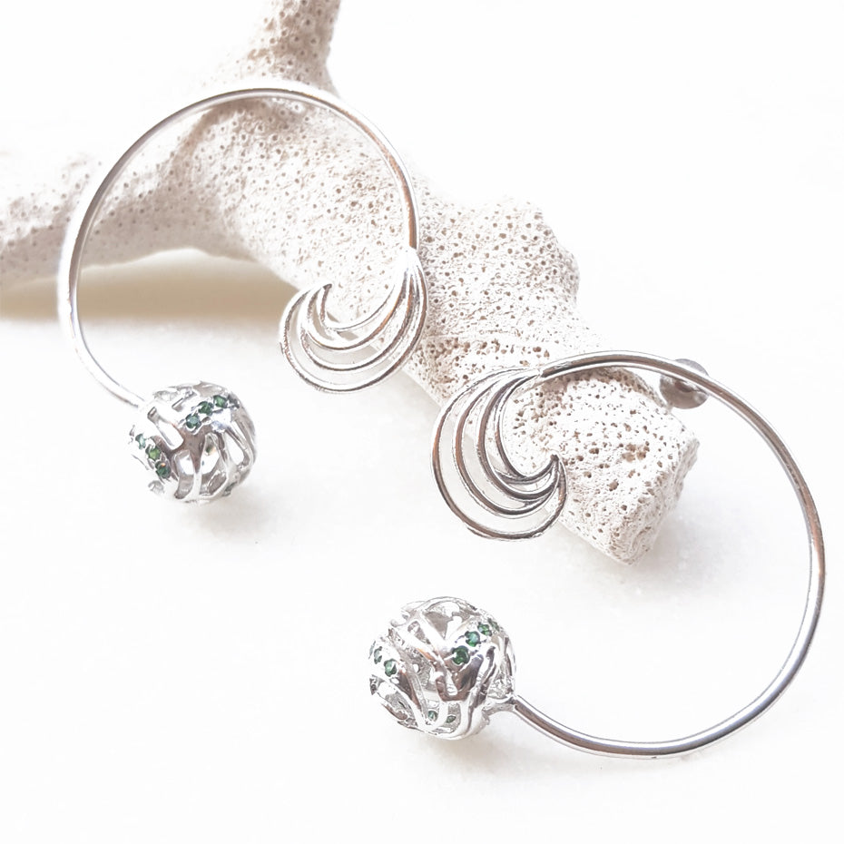 Handcrafted statement stud earrings featuring a bold, sculptural metallic wave design with a high-polished finish, isolated on a white background.